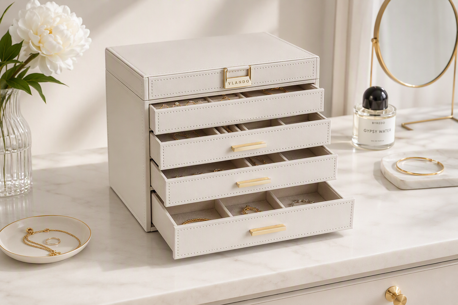 White jewelry box with drawers arranged neatly on a dresser with jewelry visible inside