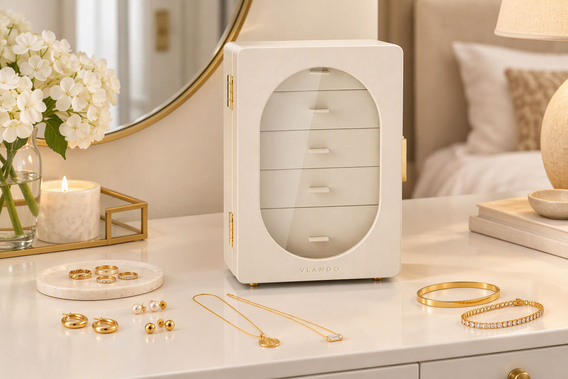 Leather jewelry box with gold-plated rings, earrings, necklaces, and bracelets arranged neatly on a vanity