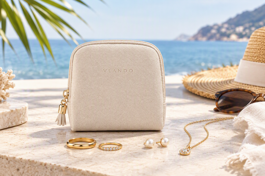 Compact VLANDO travel jewelry pouch with rings, earrings, and a necklace arranged beside it on a bright beach-resort surface.