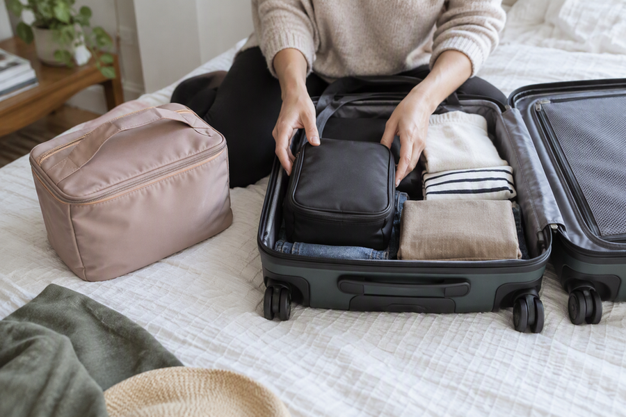 A traveler checks whether a compact makeup bag fits in an open carry-on, with a larger organizer nearby for comparison.