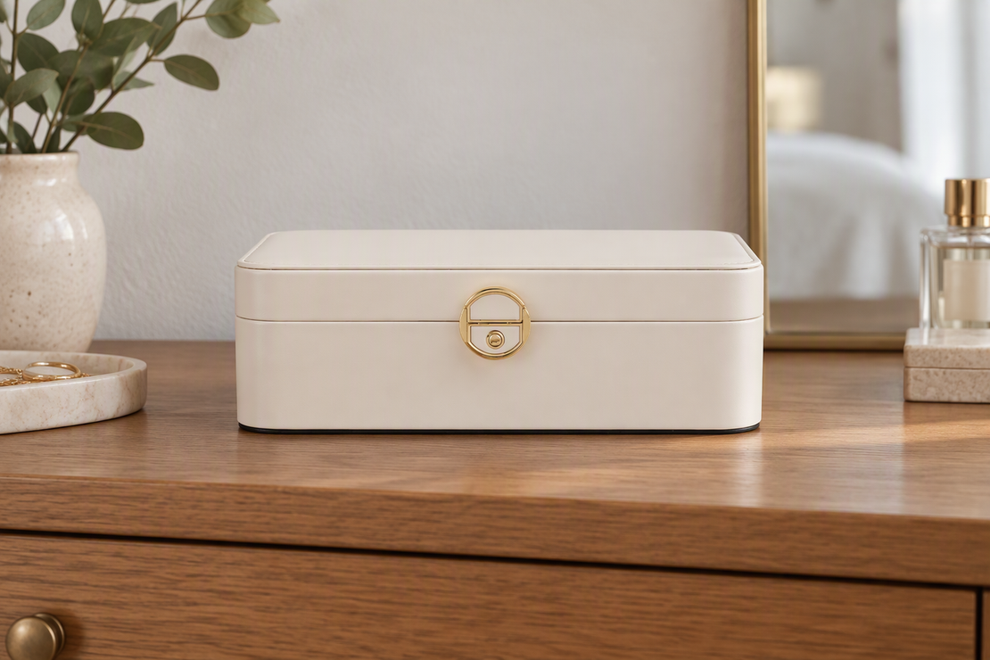 Closed creamy-white two-layer leather jewelry box with a gold-tone clasp and dark base trim.
